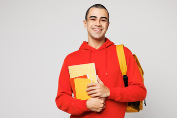 Young smiling happy smart middle eastern man boy student he wear red casual clothes backpack bag hold books look camera isolated on plain solid white background High school university college concept