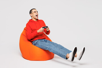 Full body young middle eastern man he wear red hoody casual clothes sit in bag chair hold in hand...
