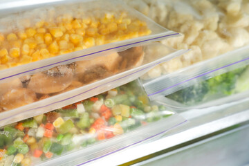 Plastic bags with different frozen vegetables in refrigerator, closeup