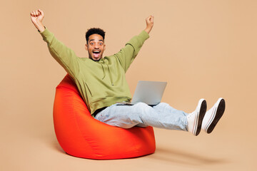 Full body young IT man of African American ethnicity wears green hoodie casual clothes hold use...