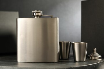 Hip flask, cups and funnel on table, closeup