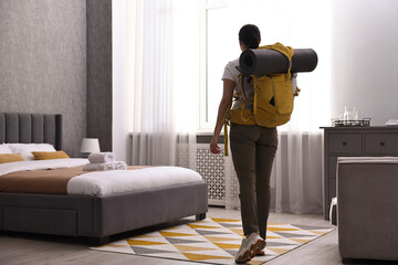 Traveller with backpack in hotel room, back view