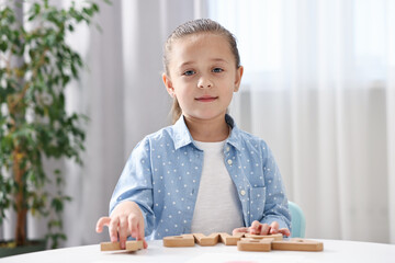 Naklejka premium Little girl learning alphabet with wooden letters at white table indoors