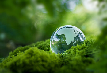 Environmental concept - Crystal globe on green moss in forest to protect nature. Eco-friendly esg...