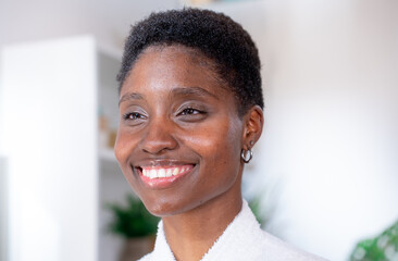 A cheerful woman with short hair smiling brightly, exuding positivity and joy in a modern indoor setting