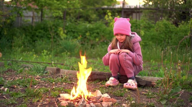 a girl near a small campfire in nature. 4k