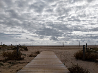 Playa en un dia nuboso con una pasarela de madera