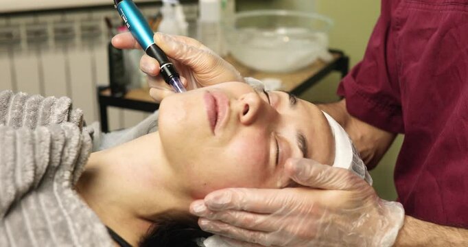 beautiful young woman on a facial dermapen micro-needling treatment at the beauty salon. Woman is getting a facial treatment with a device.