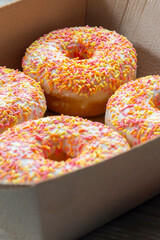 Iced ring doughnuts sprinkled with hundreds and thousands in a card tray. Recycling eco friendly biodegradeable packaging