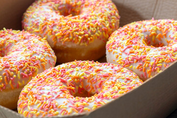 Iced ring doughnuts sprinkled with hundreds and thousands in a card tray. Recycling eco friendly biodegradeable packaging