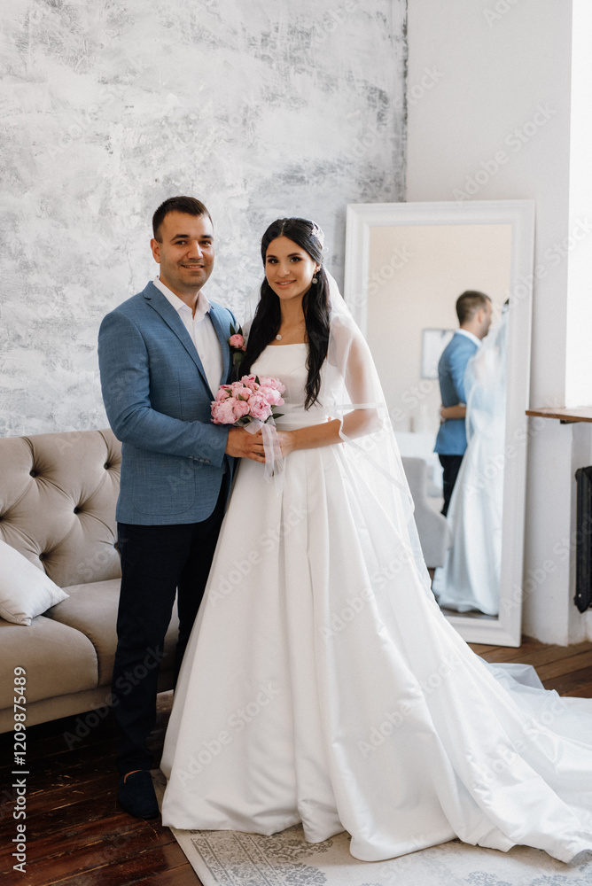 Wall mural groom in a blue suit tie and the bride in a bright studio