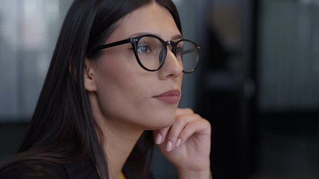 Professional woman with black-rimmed glasses nodding in agreement, conveying attentiveness and understanding in a modern office setting. Concept of professionalism and active listening