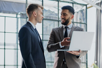 Fototapeta premium two professional businessmen discussing and using desktop computer in office