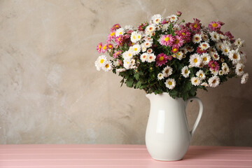 Vase with beautiful flowers on pink wooden table, space for text