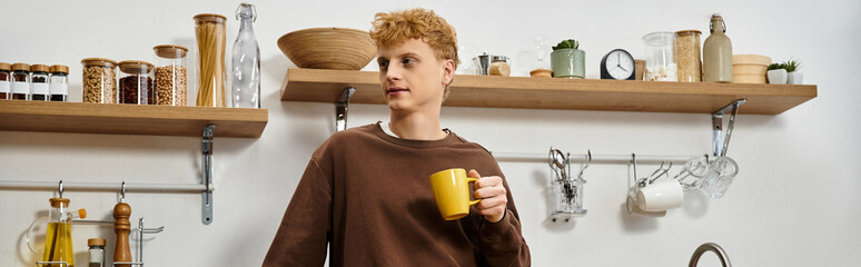 A young redhead relaxes in his modern living space, sipping coffee and embracing home life, banner