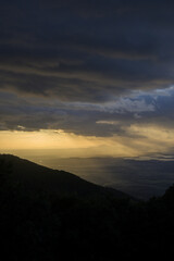 Vertical sunset landscape with sun rays filtering through the clouds