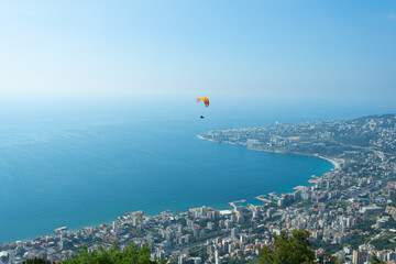Obraz premium A breathtaking paragliding experience above Beirut, showcasing the city, sea, and historic sites. Adventure tourism, sports marketing, and travel promotions.