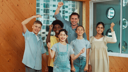 Smart teacher and diverse student standing while waving hand to camera. Skilled instructor with highschool children with mixed races in casual outfit greeting and smiling with cheerful. Edification.