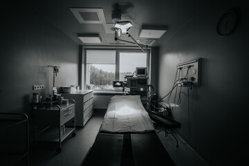 A dimly lit operating room with surgical equipment, medical monitors, and a surgical bed, creating...