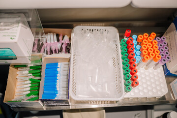 Organized medical supplies including syringes, blood collection tubes, and plastic containers,...