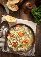 Bowl of chicken noodle soup with carrots on a napkin