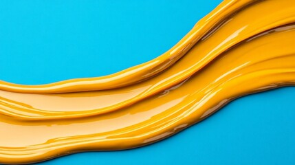 Golden Wave Abstract: A vibrant, abstract image featuring a flowing stream of rich, golden paint on a contrasting bright blue background. The texture is smooth and glossy.