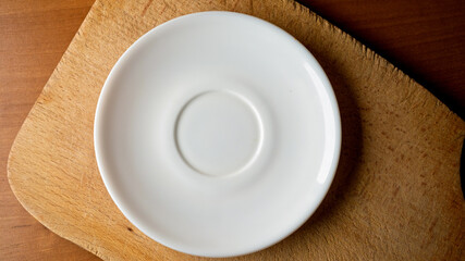 Minimalist design of a white plate on a rustic wooden board