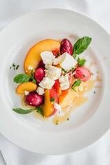 Peach and feta salad with mint and honey on a white plate