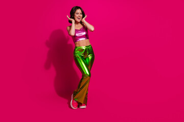 Excited young woman in vibrant clothing on bright magenta background exuding happiness and charm