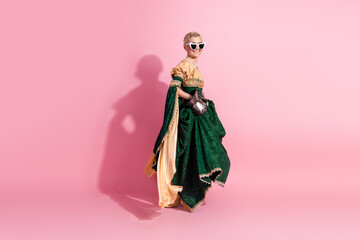 Elegant young woman in a historical dress posing against a pink background with a fun, modern twist