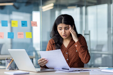 Upset and disappointed woman holding report with negative achievement results. Businesswoman at...