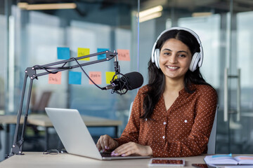 Portrait of a young female blogger, influencer laughing and looking at the camera, using a...
