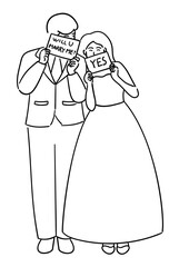 Groom is holding a sign that says Will you marry me, and the bride is holding a sign that says Yes, a cute couple on their wedding day, bride and groom 