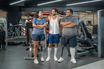 Fototapeta premium portrait happy persons with prosthetic leg,athletic couple standing with trainer in indoors gym