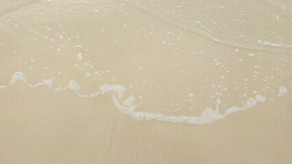 Gentle Ocean Wave Foam on Smooth Sandy Beach