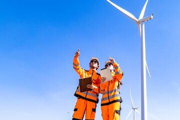 Team of male and female engineers discuss for maintenance of wind turbines at windmill field farm....
