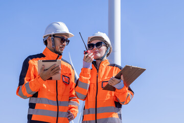 Team of male and female engineers discuss for maintenance of wind turbines at windmill field farm....
