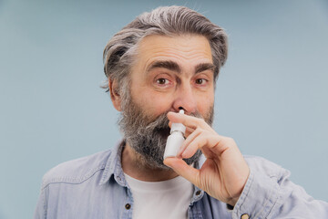 Senior Man Using Nasal Spray for Cold and Flu Relief