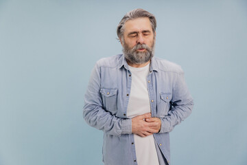 Senior man suffering from stomach ache on blue background