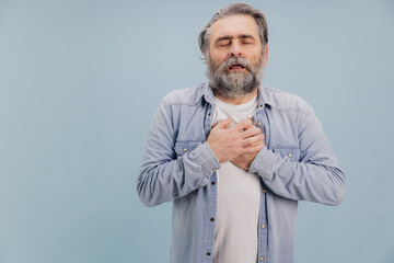 Senior man suffering chest pain on blue background