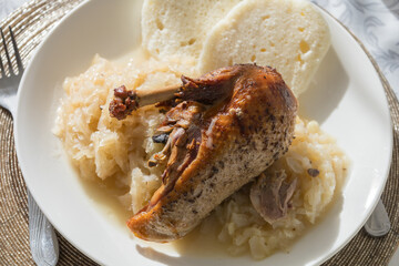 Delicious lunch - roasted duck leg, cabbage, yeast dumpling on a white plate