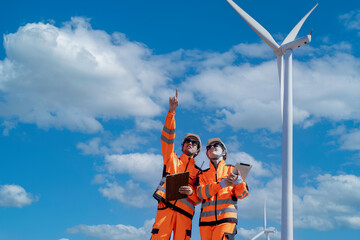 Team of male and female engineers discuss for maintenance of wind turbines at windmill field farm. Group of engineers workers working at wind turbines farm. Alternative energy, environmental friendly.