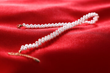 Beautiful pearl necklace on red cloth, closeup