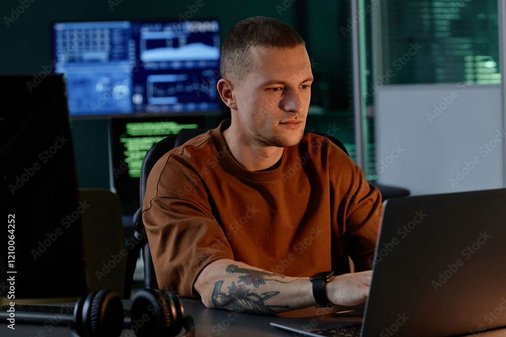 Poster medium shot of young male software developer immersed in coding on laptop, while sitting in light fr