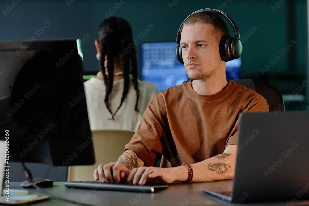 Aufkleber medium shot of confident male programmer wearing headphones writing code on desktop computer while w
