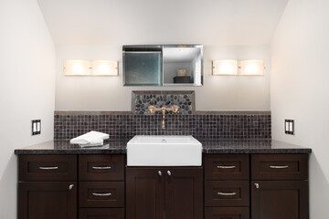 Modern bathroom interior design featuring dark brown cabinetry, a white farmhouse sink, square and...