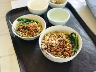 Delicious mi ayam with separate pangsit and savory broth Enjoy the perfect combination of tender chicken, crispy wontons, and flavorful soup. South Jakarta, Indonesia - April 21, 2023