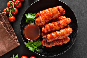 Bacon wrapped sausages with barbecue sauce on plate