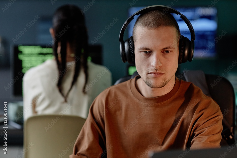 Aufkleber portrait of senior male developer in headphones intently coding on laptop while working in evening h