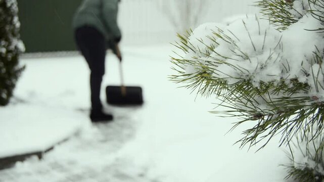 Woman cleaning her snowed back yard with plastic shovel. Winter concept.
